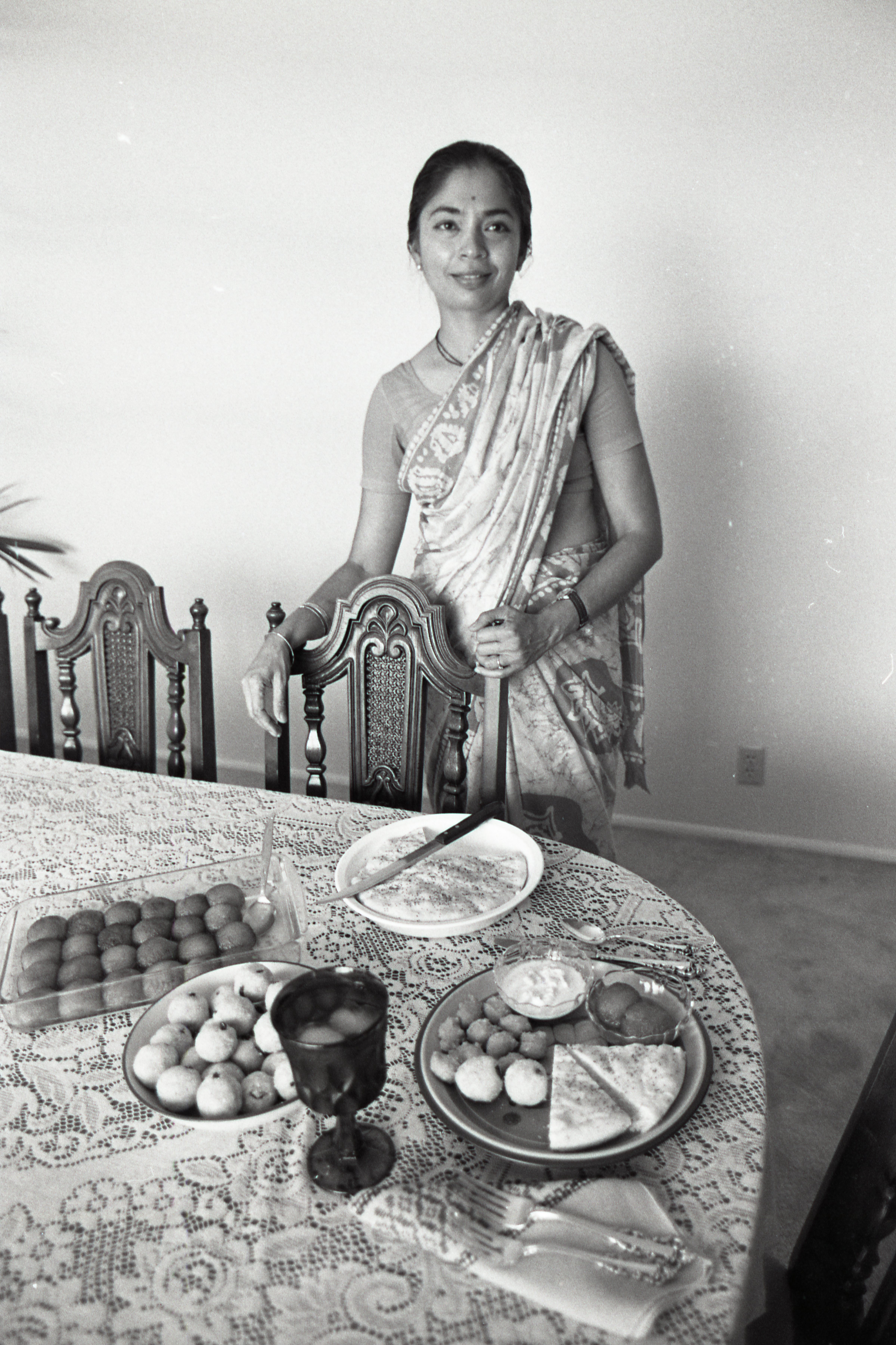 Neila Sheshachari wearing traditional clothing in front of a table with several food items.